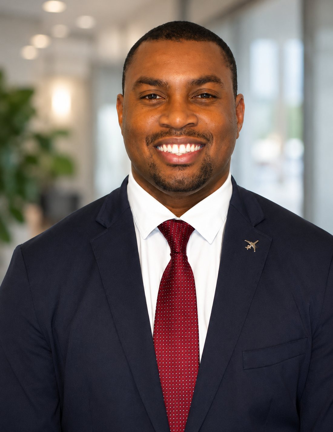 Cam Parker in a navy suit with an airplane lapel pin